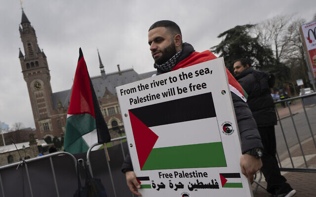 A pro-Palestinian, anti-Israel demonstrator holds a sign outside the International Court of Justice, rear, in The Hague, Netherlands, February 21, 2024. (AP Photo/ Peter Dejong) A pro-Palestinian, anti-Israel demonstrator holds a sign outside the International Court of Justice, rear, in The Hague, Netherlands, February 21, 2024. (AP Photo/ Peter Dejong)