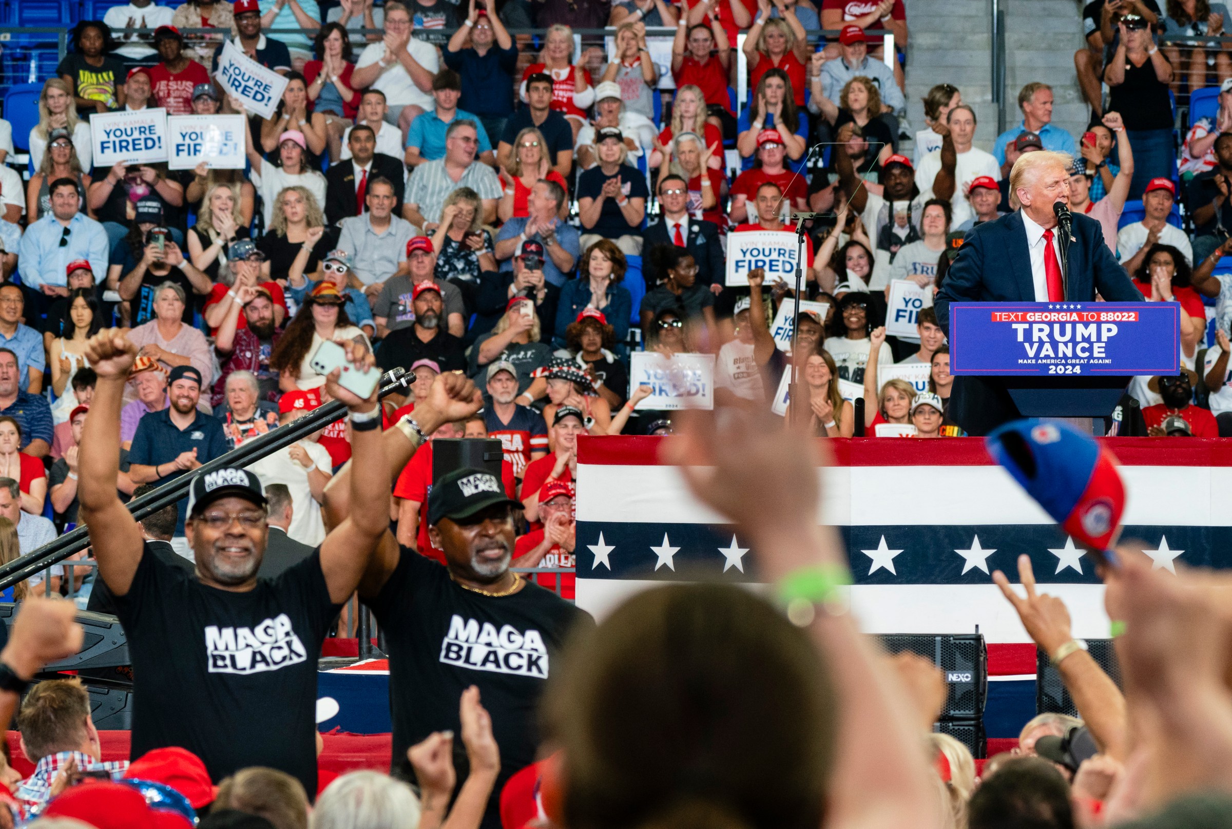 ATLANTA, GA - AUGUST 3- Two men wearing Black MAGA' shirts sta