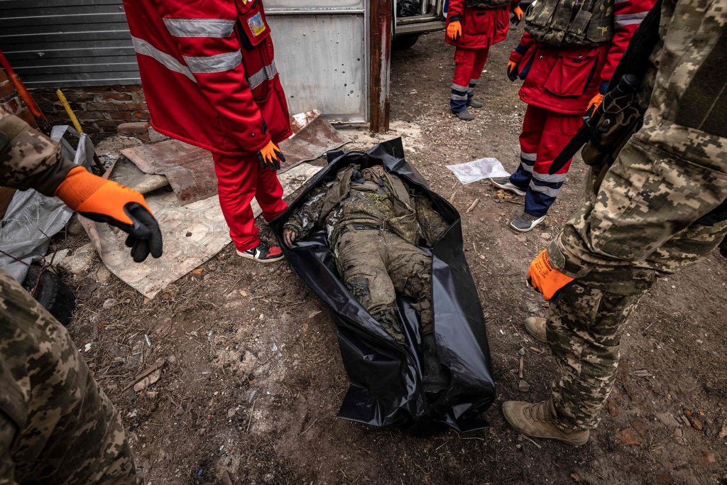 Ukrainian medics carry the body of a Russian soldier after Ukrainian troops retook the village of Malaya Rohan.