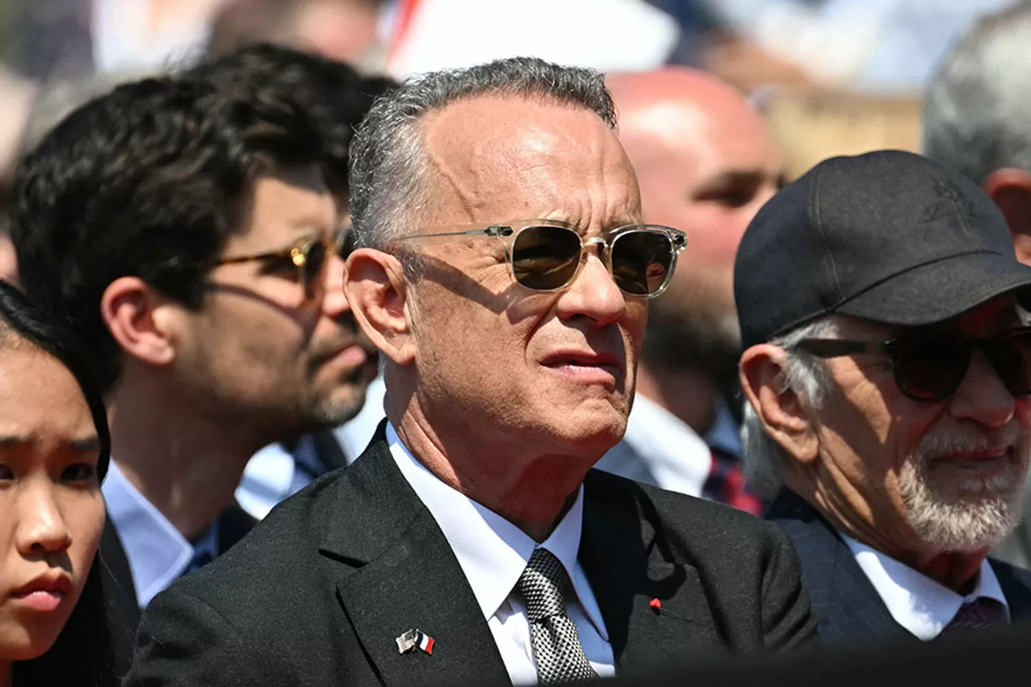 US actor Tom Hanks (C) and US director Steven Spielberg (R) attend the US ceremony marking the 80th anniversary of the World War II D-Day Allied landings in Normandy, at the Normandy American Cemetery and Memorial in Colleville-sur-Mer, which overlooks Omaha Beach in northwestern France, on June 6, 2024. The D-Day ceremonies on June 6 this year mark the 80th anniversary since the launch of 'Operation Overlord', a vast military operation by Allied forces in Normandy, which turned the tide of World War II, eventually leading to the liberation of occupied France and the end of the war against Nazi Germany. 