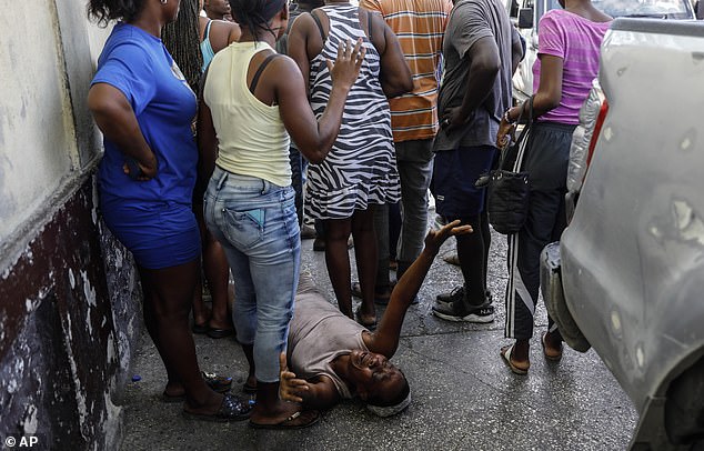 82302055-13181341-A_woman_lies_on_the_pavement_as_she_mourns_a_family_member_shot_-a-94_1710136133434.jpg