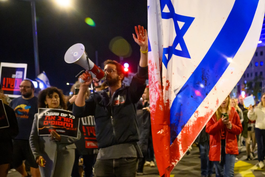 A protester with red paint on his hand marches through the streets after demonstrating outside the Israel Defense Forces headquarters.