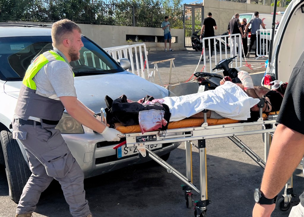 A Civil Defense first-responder carries a wounded man at al-Zahraa hospital in Beirut, Lebanon, on Sept. 17.