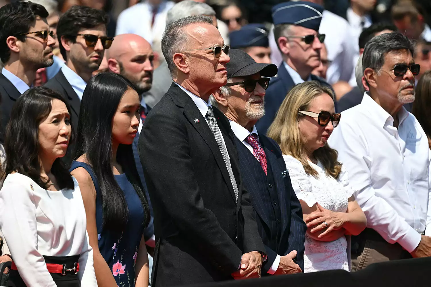 US actor Tom Hanks (C) and US director Steven Spielberg (center R) attend the US ceremony marking the 80th anniversary of the World War II D-Day Allied landings in Normandy, at the Normandy American Cemetery and Memorial in Colleville-sur-Mer, which overlooks Omaha Beach in northwestern France, on June 6, 2024. The D-Day ceremonies on June 6 this year mark the 80th anniversary since the launch of 'Operation Overlord', a vast military operation by Allied forces in Normandy, which turned the tide of World War II, eventually leading to the liberation of occupied France and the end of the war against Nazi Germany. 