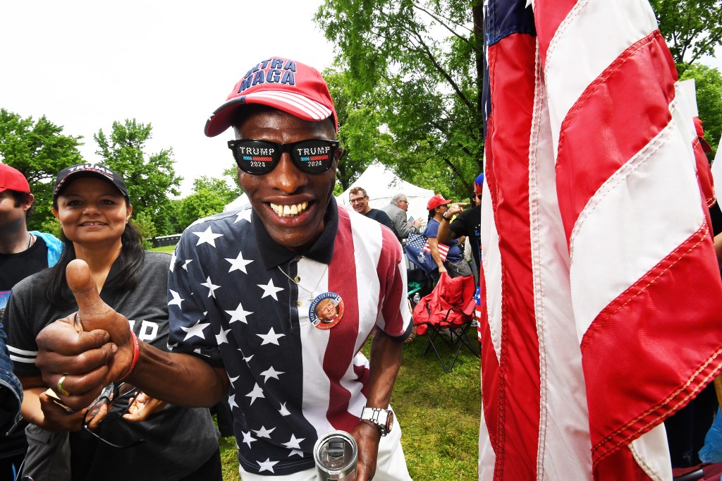 A Trump supporter decked out in an American flag shirt and Trump sunglasses.
