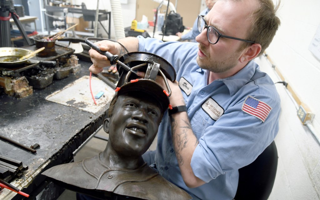 David Hobbs, an employee at Art Castings of Colorado, touches up a wax mold of Jackie Robinson's head in Loveland, Colo. on Wednesday, May 8, 2024. 