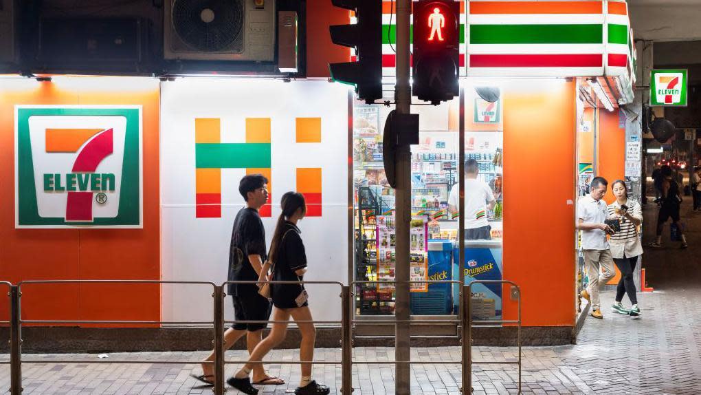 Pedestrians walk past a convenience store 7-Eleven in Hong Kong.