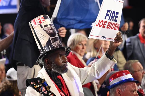 an-attendee-with-an-abraham-lincoln-top-hat-waves-a-fire-biden-sign-during-the-last-day-of.jpg