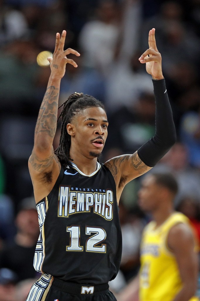 Ja Morant in his Memphis jersey raising his hands in the air. 