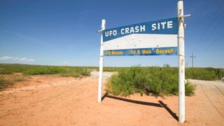 a sign in the desert that reads ufo crash site, ufo museum 114 north main street, roswell