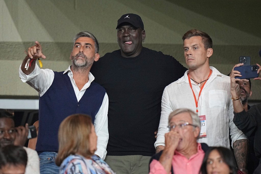 Michael Jordan, center, gestures as he attends the Champions League opening phase soccer match between Monaco and Barcelona